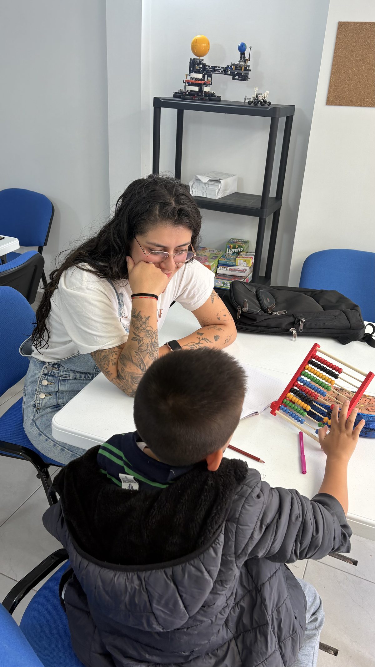 Tutora de Explora Lab acompañando a un estudiante de primaria con un ábaco